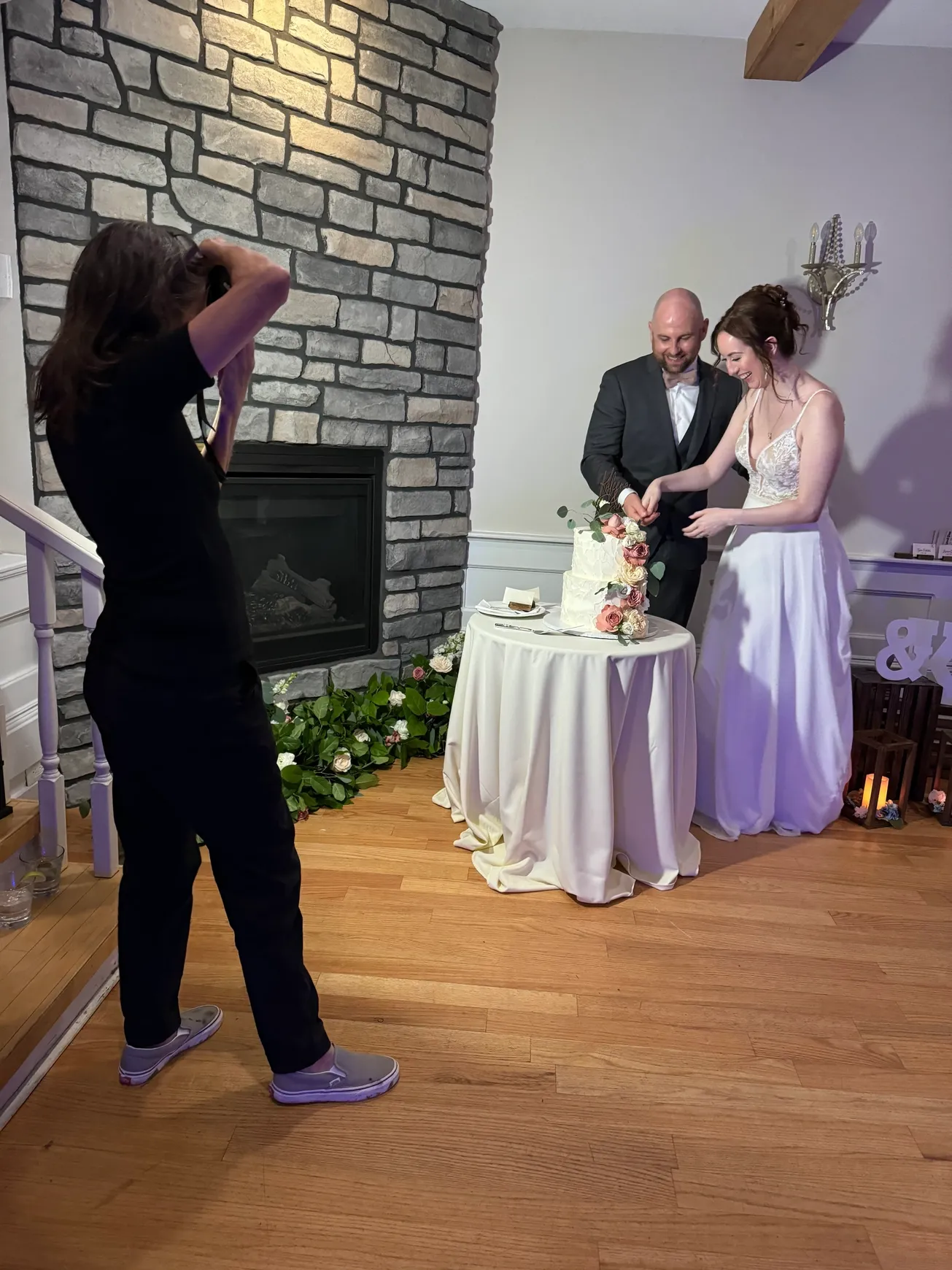 Newlyweds cutting their wedding cake by the fireplace